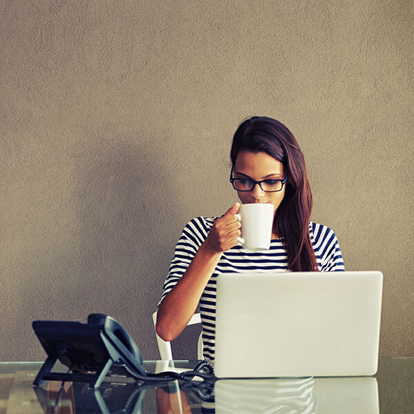 Woman drinking coffee with laptop